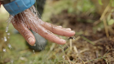 slow motion - hose being used to wash asian hands during gardening