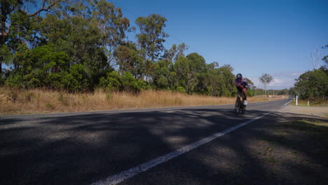 Fast-Cyclist-Speeding-Past-On-Rural-Countryside-Asphalt-Road,-4K,-Australia