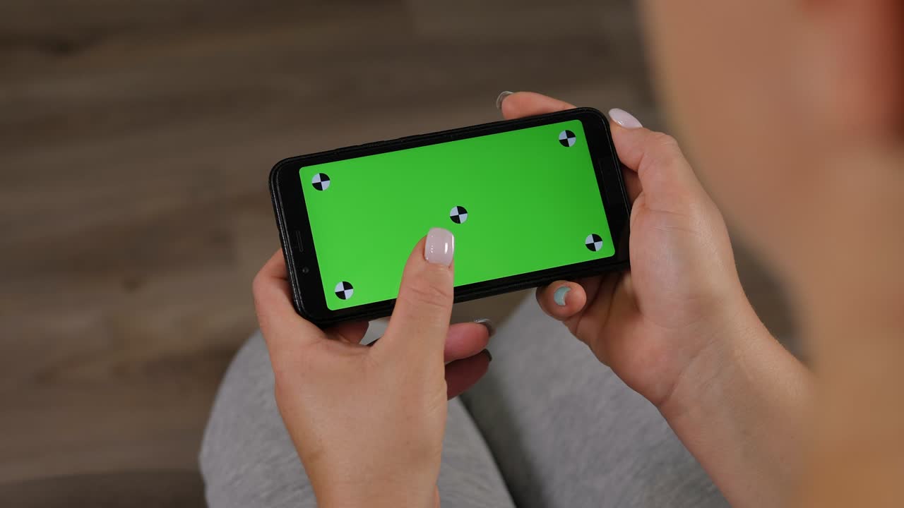 집에서 초록색 화면을 가진 드폰을 들고 있는 여성의 클로즈업입니다.