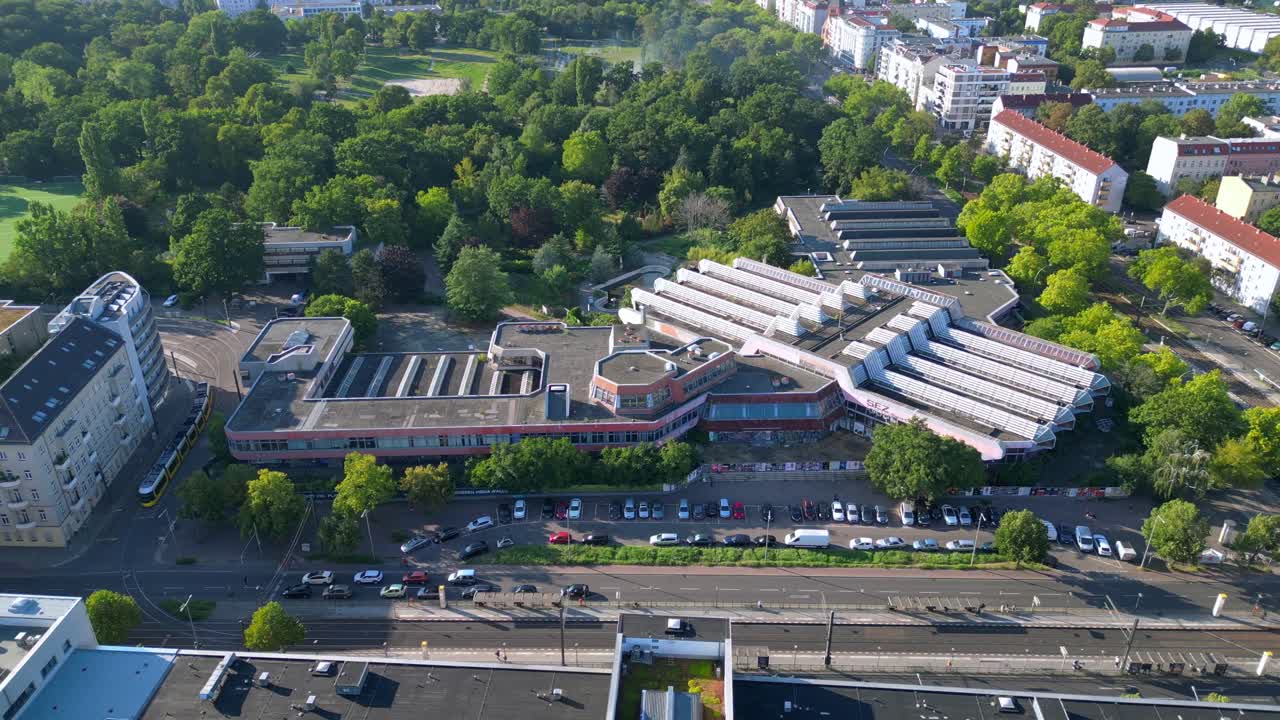 Sez and Volkspark Friedrichshain in Berlin, showcasing its lush greenery, a passing tram on a sunny day. Smooth aerial view flight circle drone footage