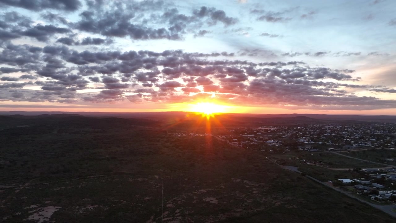 Sol dourado nasce acima do horizonte com vista para Broken Hill em uma vista aérea cinematográfica de drone através do remoto interior australiano.