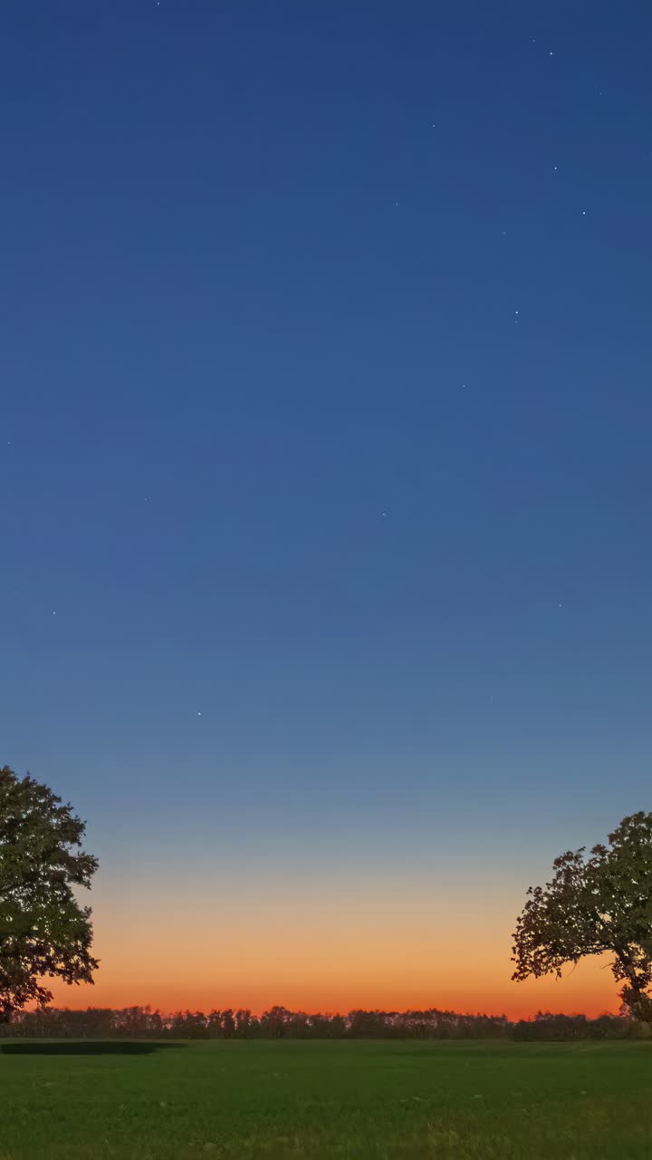 Dawn timelapse as soft light gradually reveals fields and sky shifting from night to day