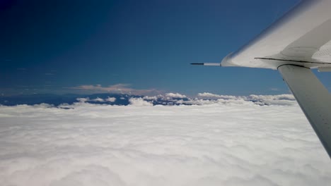 flying above thick white clouds in small airplane, view of wing