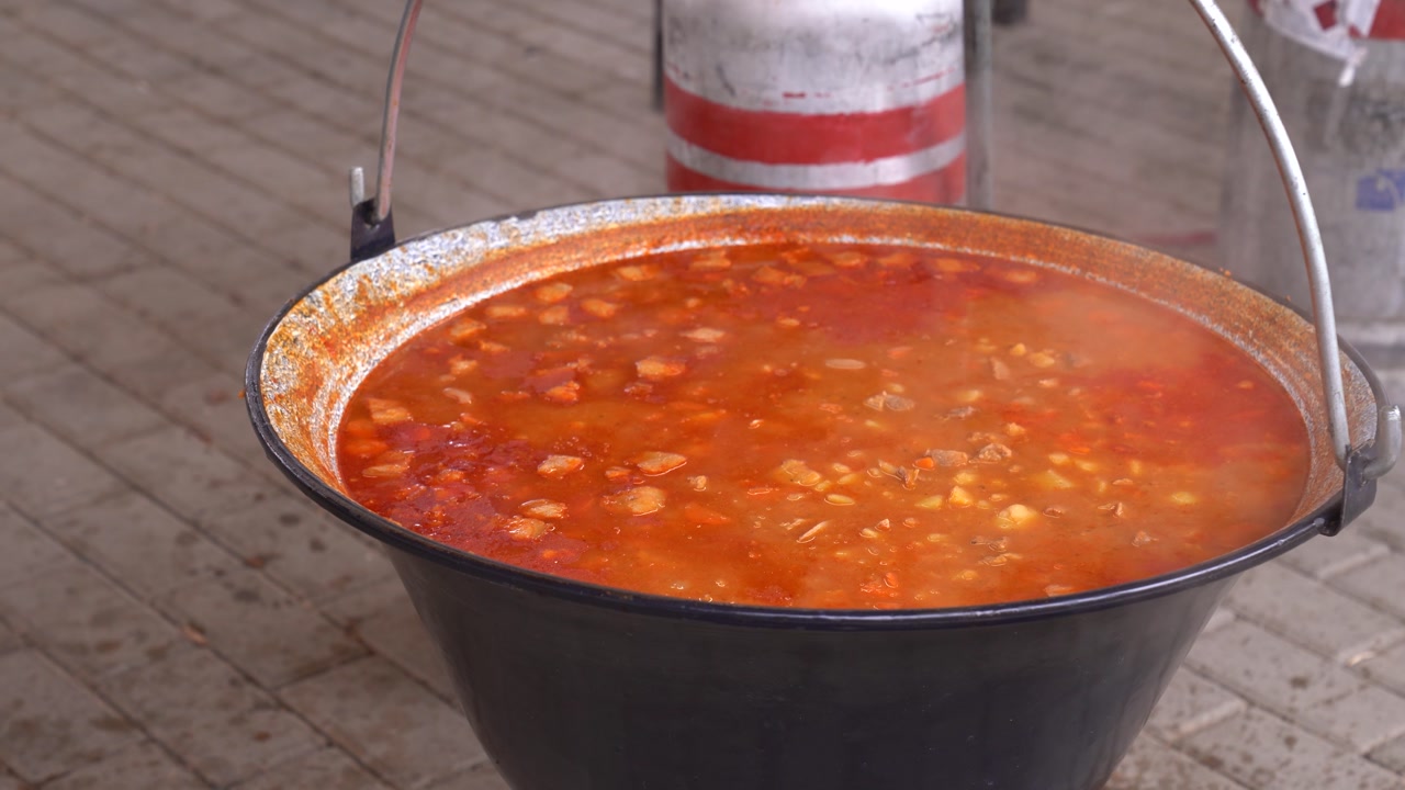 Spicy Hungarian goulash soup cooking in a large cauldron pot