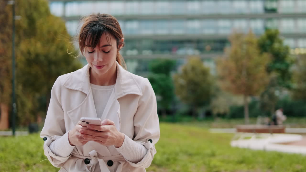 Giovane donna che usa uno smartphone in un moderno parco urbano