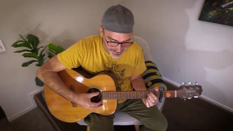 an expressive man teaches and talks to young children while playing the guitar