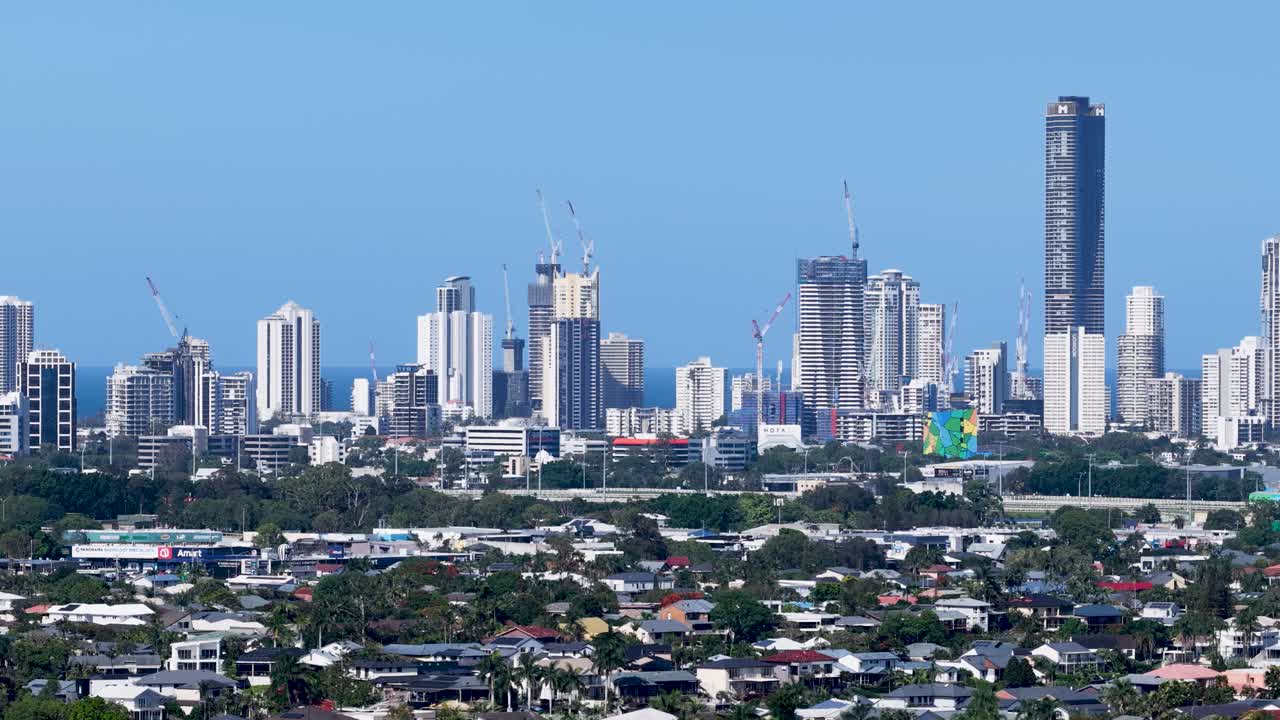Static aerial shot of Gold Coast skyline above residential suburb under bright clear daylight