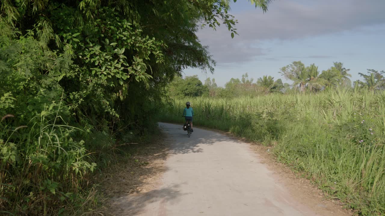 여성 사이클 선수가 카메라 뒤에서 블라인드 커브로 들어가는 텅 빈 거리를 향해 지나가는 고정 영상