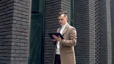 handsome businessman using tablet. young man texting messages, cheating on his tablet near the office