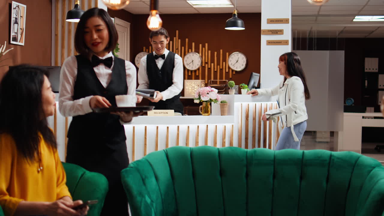 una mujer asiática le pregunta a la recepcionista acerca de la reserva de la habitación.