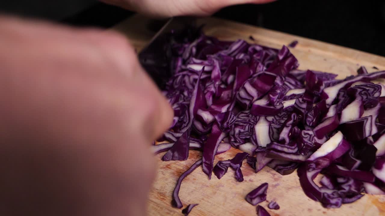 Chef chopping red cabbage on wooden cutting board in slow motion