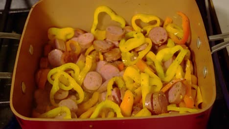 sausage and pepper being cooked in a copper pan