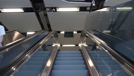 escalators in an underground station with halloween-themed neon lights, with and without people