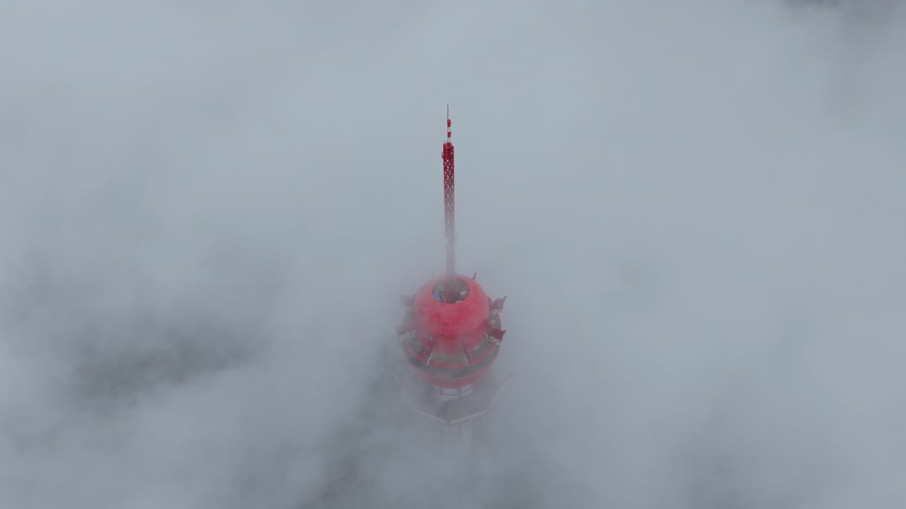 Tour de communication rouge entourée de nuages en mouvement, vue aérienne