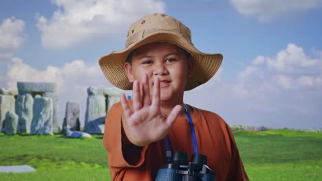 asian boy with a hat and binoculars using the magnifying glass, showing hand no gesture while traveling in stonehenge. boy researcher, travel tourism adventure, close up