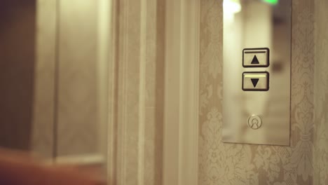 young woman pushing lift button down and entering into elevator