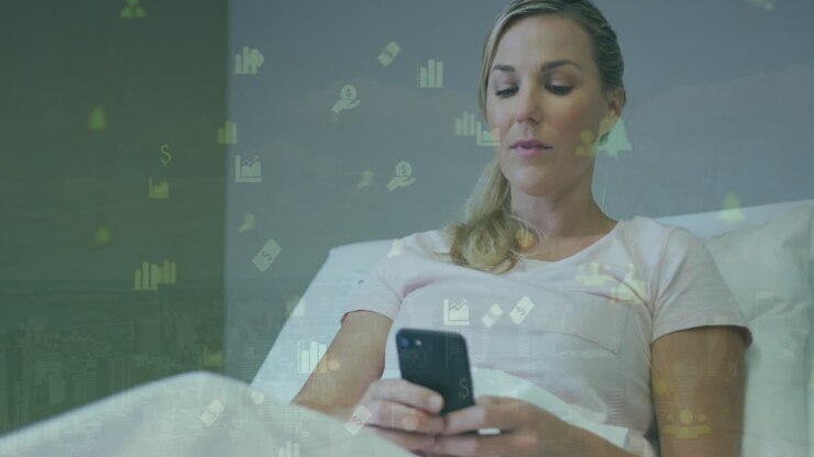Animation of network of financial icons over caucasian woman using smartphone in the bed at home