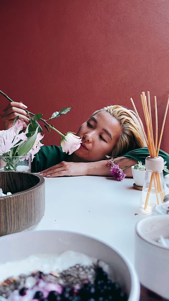 mujer disfrutando de una flor y un desayuno saludable