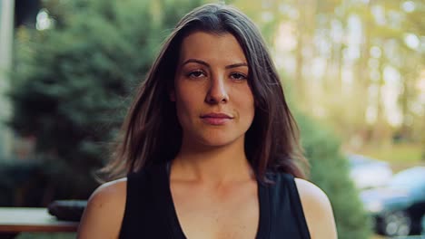 una mujer joven con una camiseta negra se toma un tiempo para reflexionar sobre su entrenamiento de la hora dorada inmediatamente después de un riguroso entrenamiento cardiovascular en una brisa suave con su cabello moreno soplando en el viento