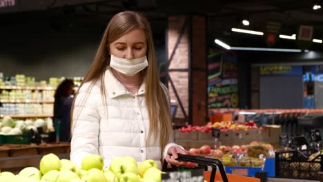 young woman in a medical mask buys fruit. self-isolation mode announcement (covid-19)