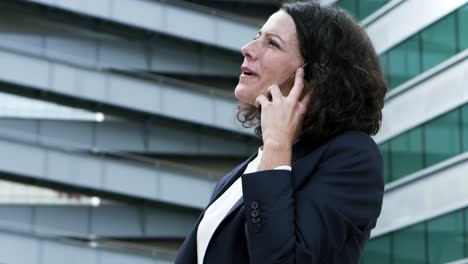 Happy-businesswoman-talking-by-smartphone