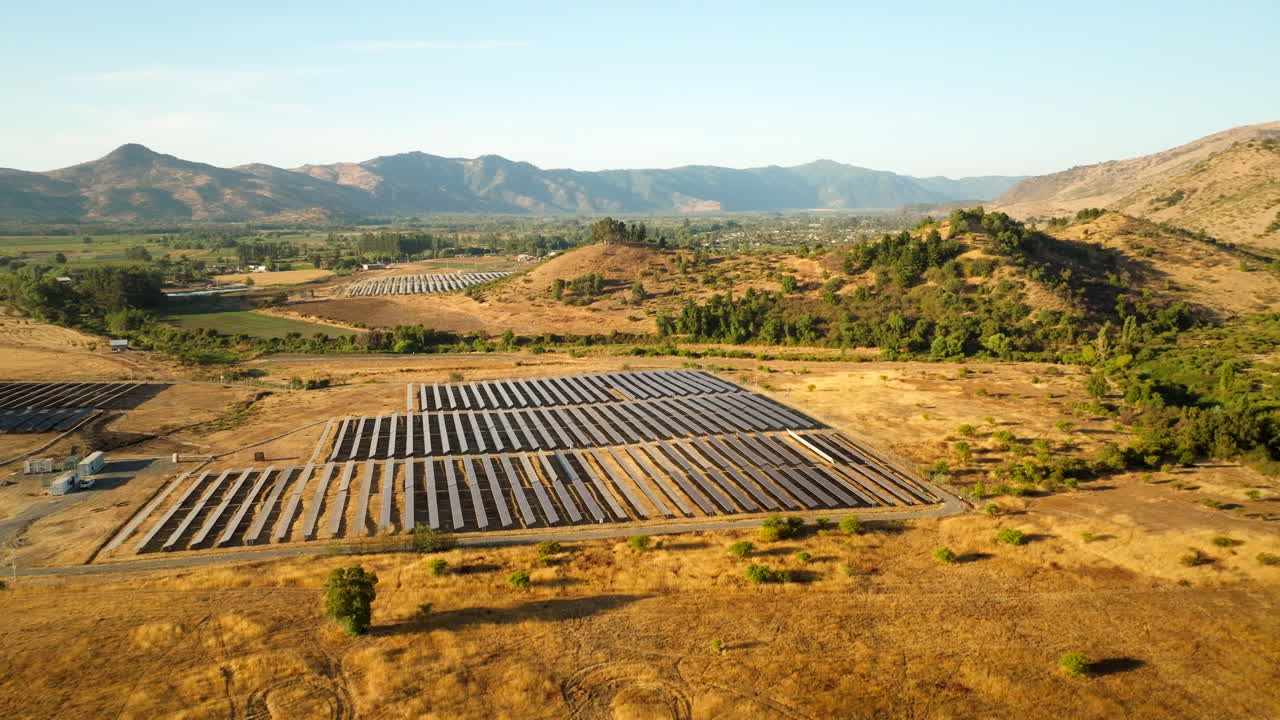 Arcing aerial view of Romeral solar park in South America with rows of PV panels