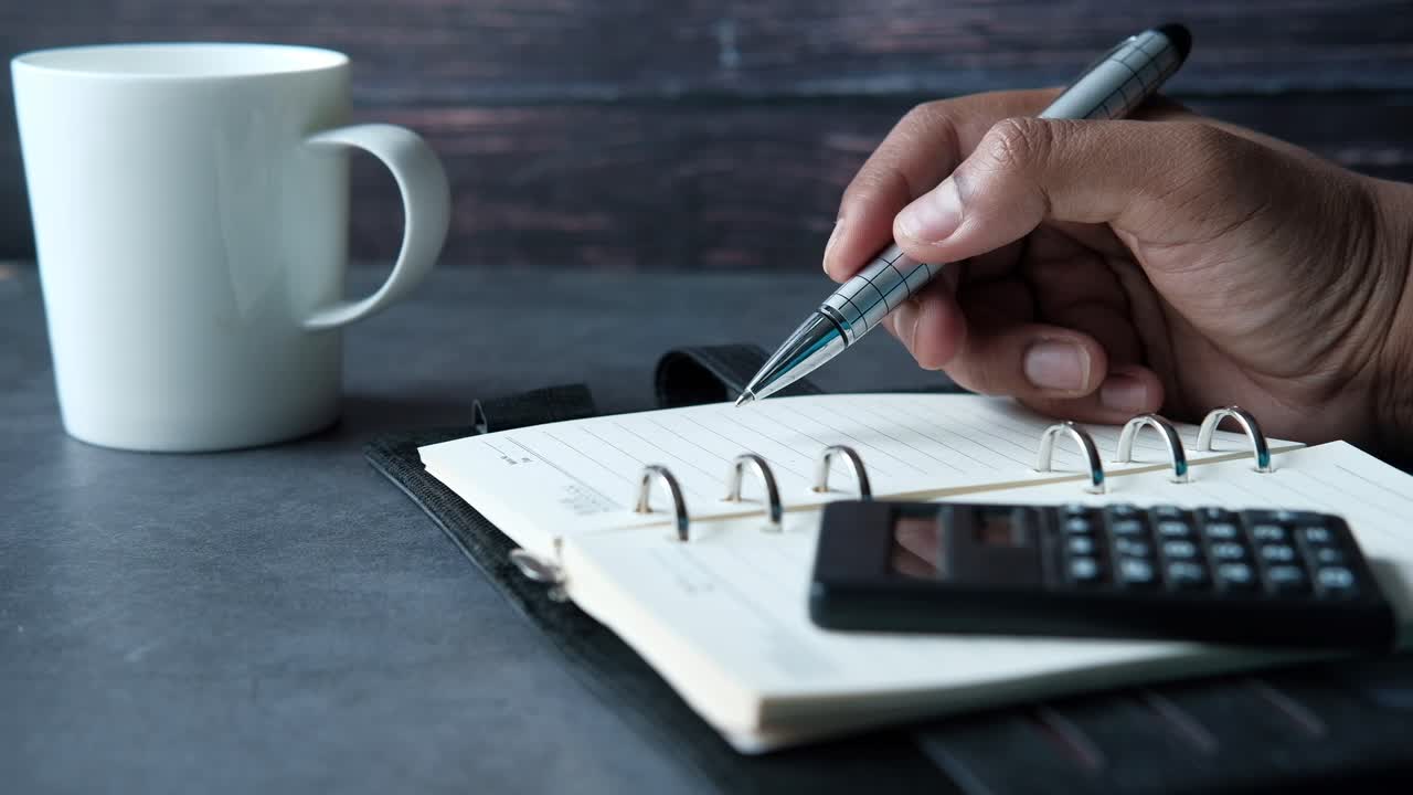 persona escribiendo en un cuaderno en un escritorio