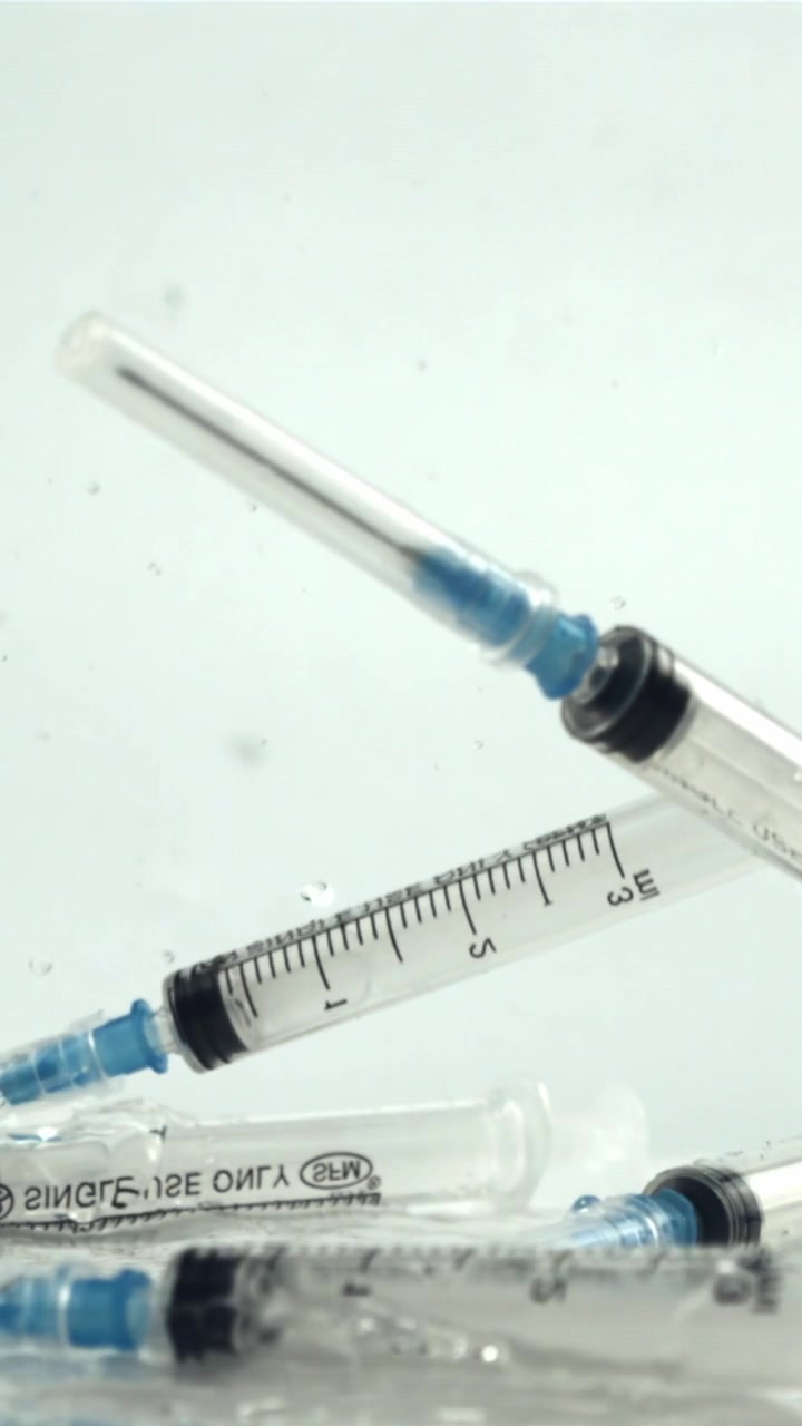 Medical Syringes Falling into Water in Slow Motion