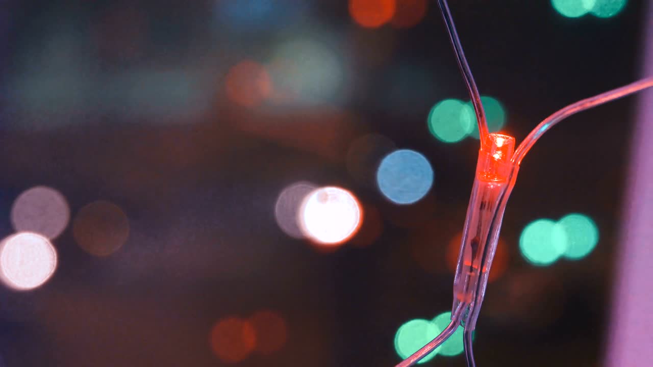 Ghirlanda natalizia con luci colorate vicino alla finestra, sullo sfondo della città e del movimento delle auto, primo piano. Luci di Natale sfocate. Bokeh.