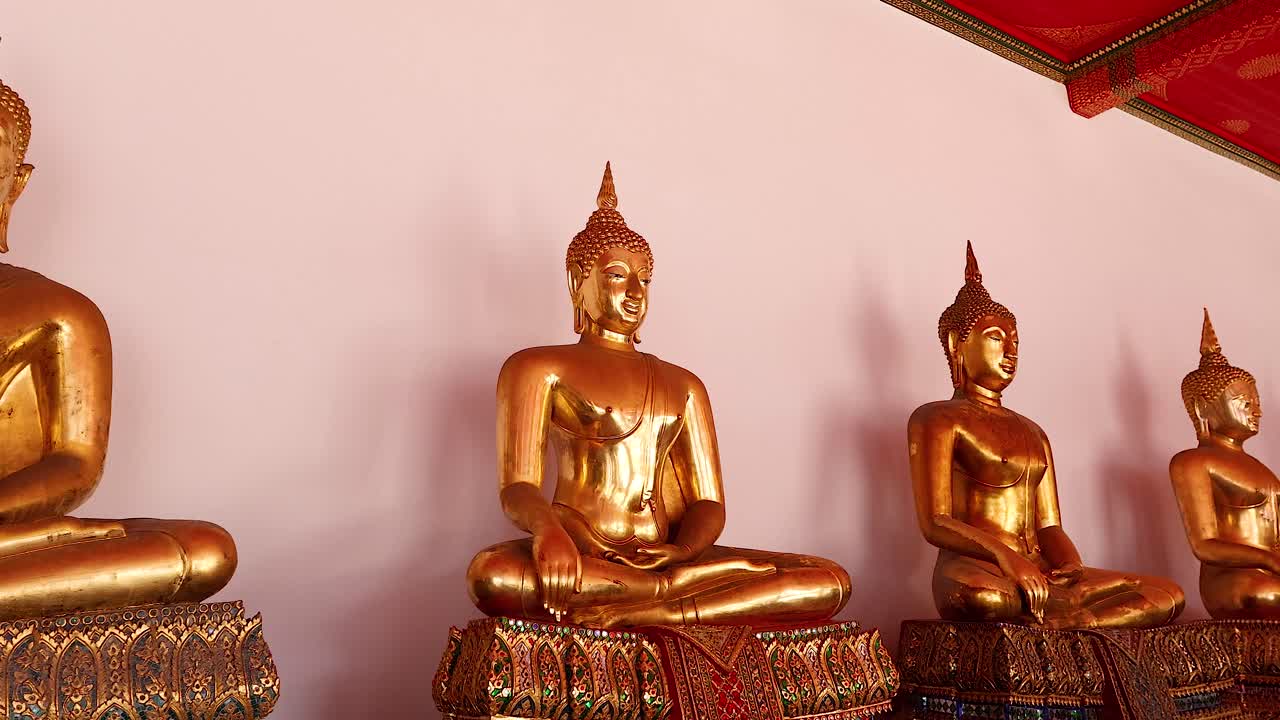 una fila de estatuas de buda de oro en wat pho