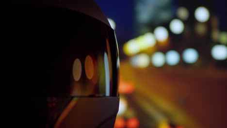 city lights and night traffic reflected on a focused motorcycle helmet