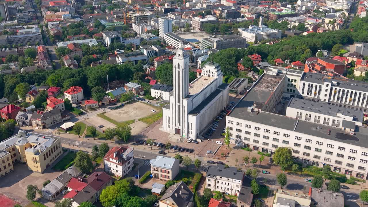 Aerial view of central Kaunas, Lithuania, featuring the iconic Resurrection Church surrounded by residential and commercial buildings on a sunny summer day