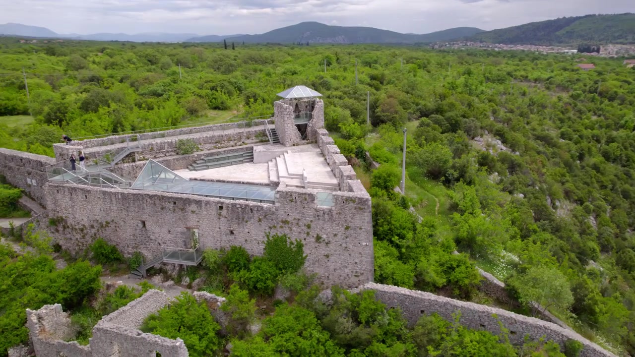 La fortezza in pietra di Počitelj corona una collina boscosa sopra il villaggio storico in Bosnia ed Erzegovina, orbita aerea di architettura medievale e ottomana