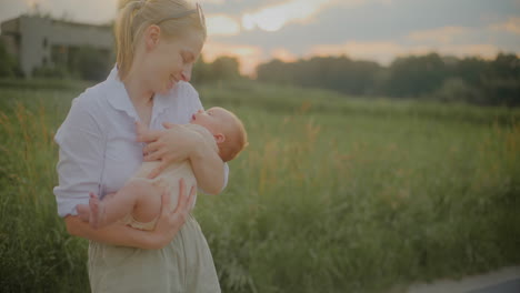 mother kissing newborn son at sunset
