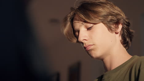 Young-boy-plays-piano-at-home-with-golden-sunlight-on-face