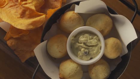 Un-Primer-Plano-Giratorio-Estacionario-De-Un-Tazón-Lleno-De-Tocino-Y-Papas-Fritas-Cubierto-Con-Queso-Cheddar-Y-Cubierto-Con-Cebolletas,-Acompañado-Con-Rodajas-De-Papa-Frita