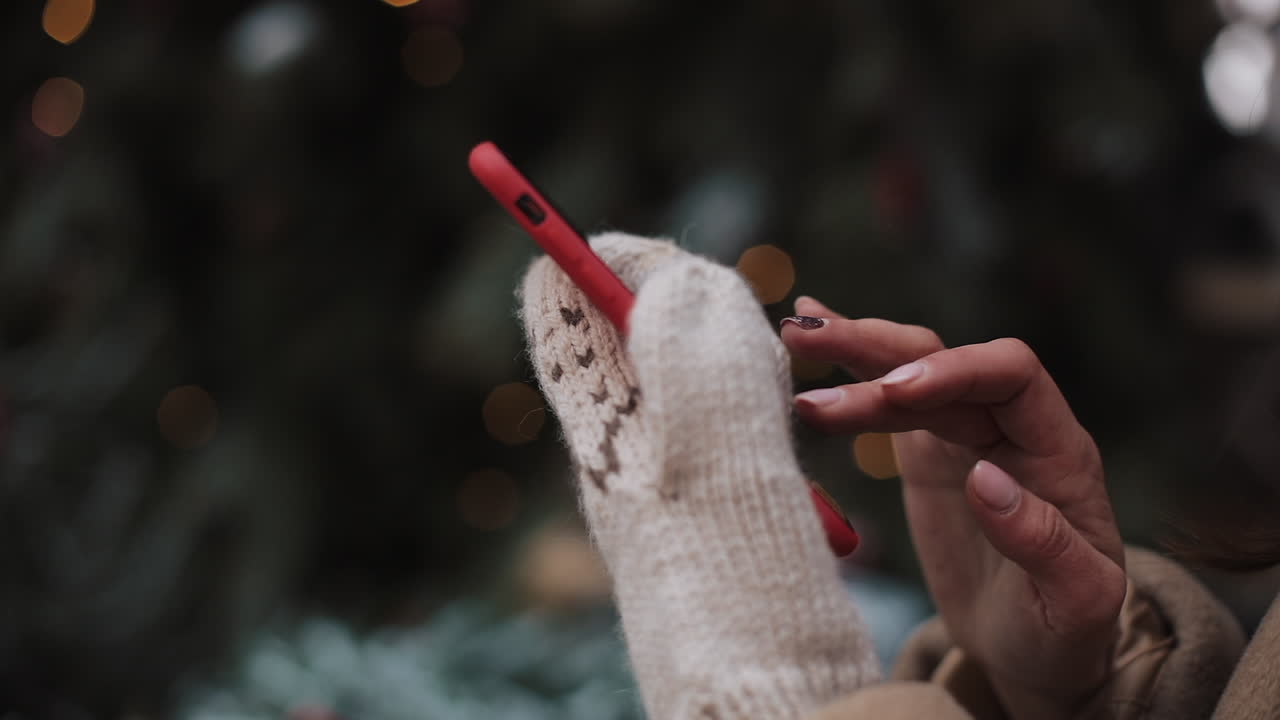 Woman using smartphone with Christmas tree in background
