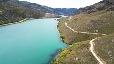 Vista-Aérea-Hacia-Adelante-Sobre-Una-Fascinante-Corriente-De-Agua-Entre-Colinas