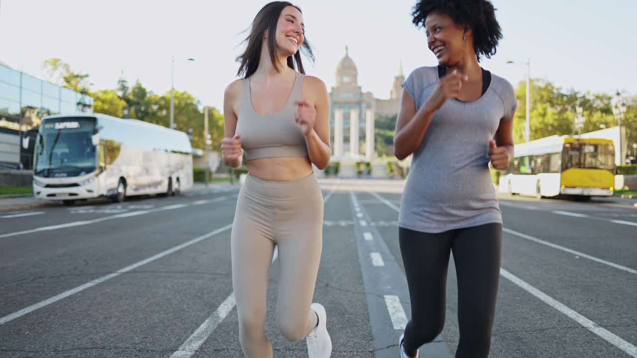 Due donne felici che corrono e parlano su una strada cittadina.