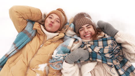 two happy girls lying in the snow