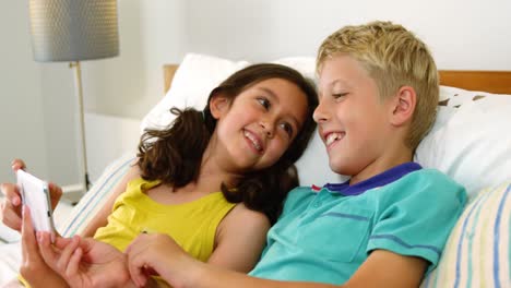 siblings using mobile phone in bedroom