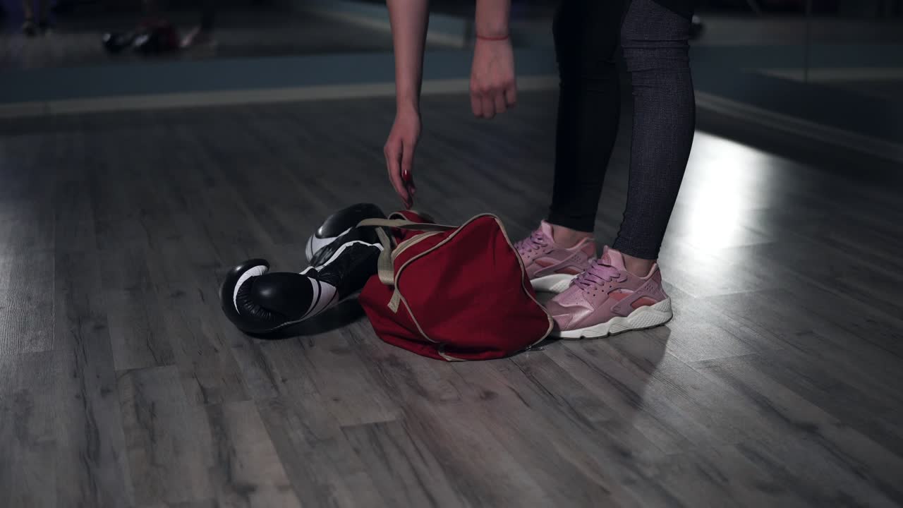 Closeup view of woman's legs walking in a boxing club. Young female boxer putting down her bag and taking out a bottle with water preparing for training. Shot in 4k