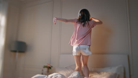 아침에 재미있는 여자 댄스 침대. 흥분 행복한 여자 헤드폰으로 음악을 듣고