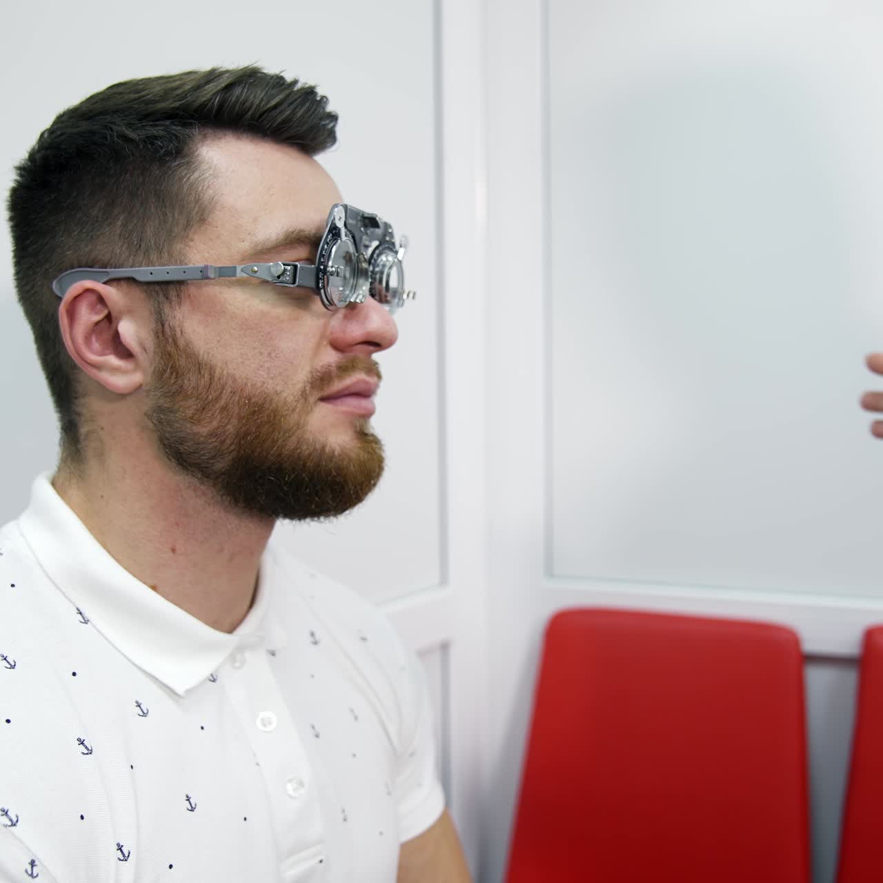 Checking eyesight. Doctor customises lenses on trial frame to a patient. Profile view of a young man in testing glasses in optical clinic