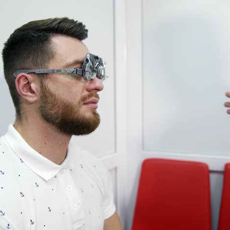checking eyesight. doctor customises lenses on trial frame to a patient. profile view of a young man in testing glasses in optical clinic