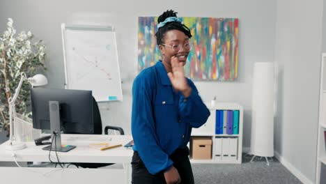 elegant feisty girl dressed in blue shirt and stylish glasses, dancing in the middle of the office, waving her arms forward, happy for the success of the company, businesswoman with a smile on face