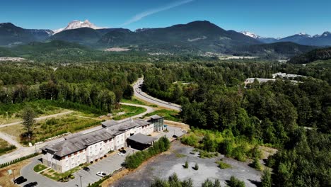 scenic road surrounded with green lush vegetation in squamish, british columbia, canada - aerial shot