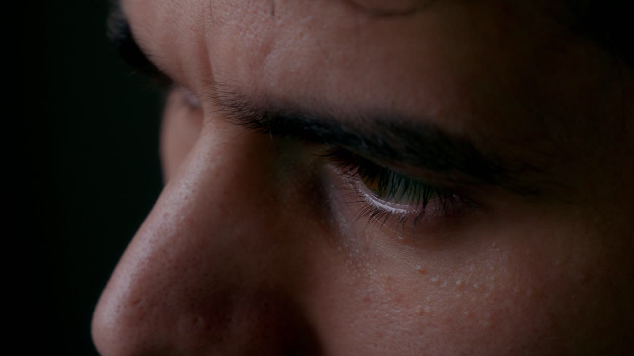 Extreme close-up of a man’s eyes looking downward at a screen, highlighting intense focus, concentration, and mental effort