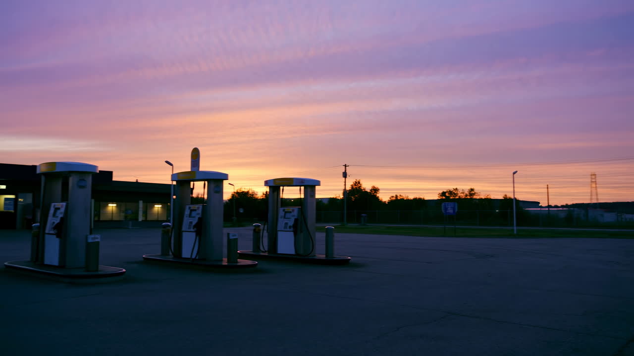 Leere Tankstelle in der Dämmerung mit leuchtendem lila und orangefarbenem Himmel
