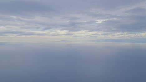 vast, calm ocean under cloudy sky with distant mountains on the horizon